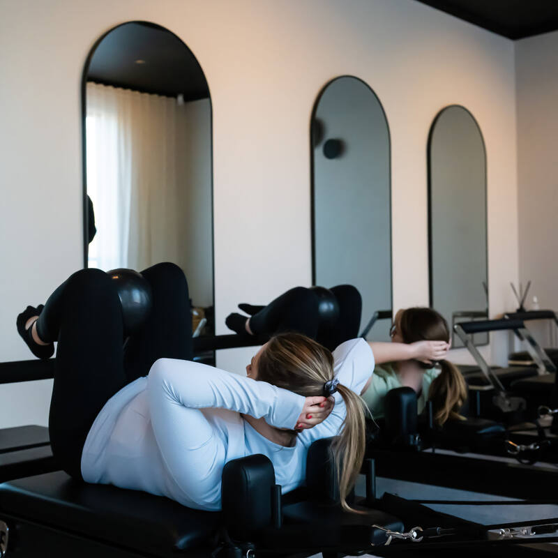 A member stretching on a Reformer in the Pilates studio